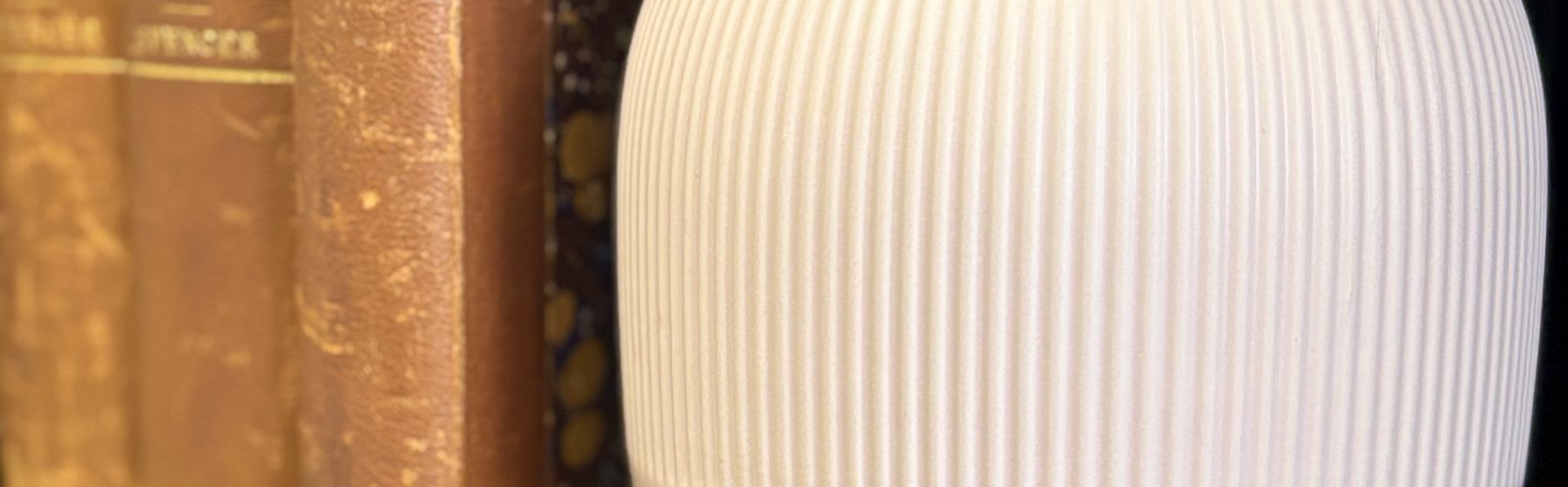 A ribbed vase beside old books on a shelf in the Sorrel office